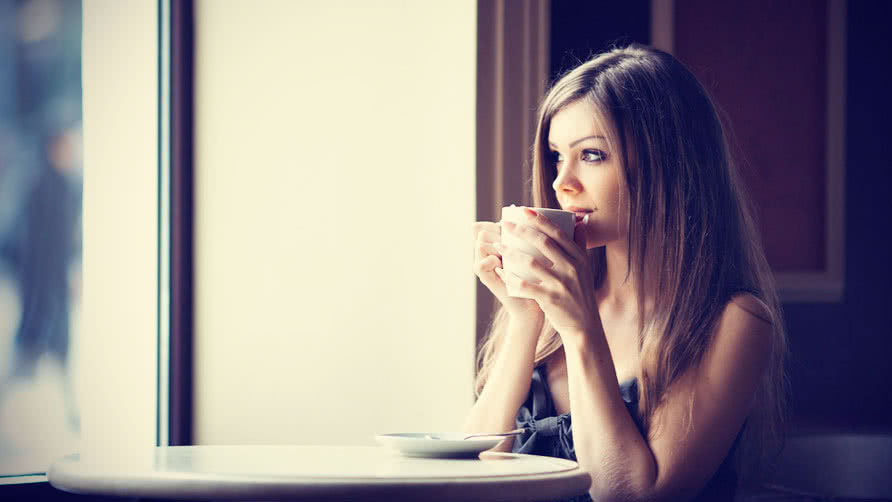 Beautiful young woman with a cup of tea at a cafe