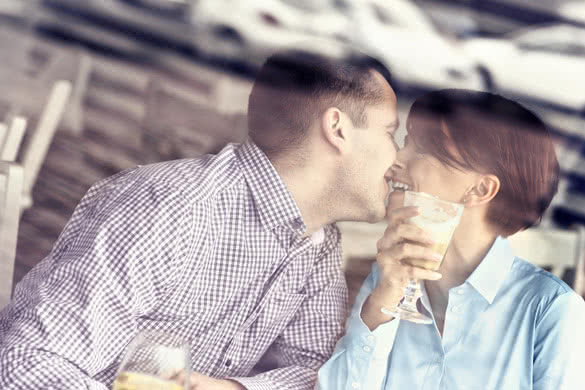 young couple kissing in a restaurant taken through a window