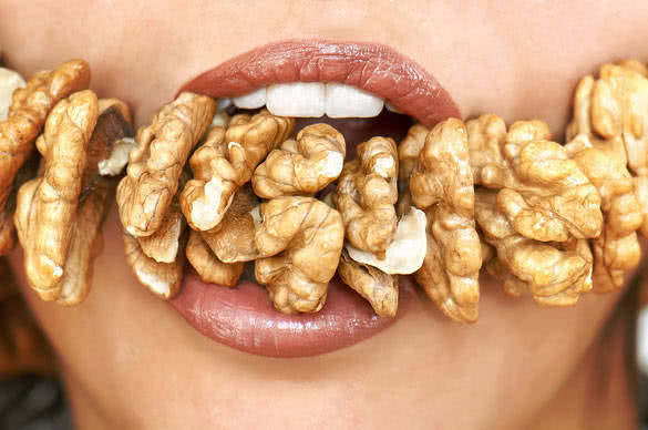 Female mouth eating a chain of walnuts