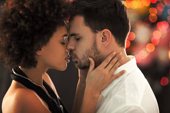 Mixed-race couple hugging gently at a party