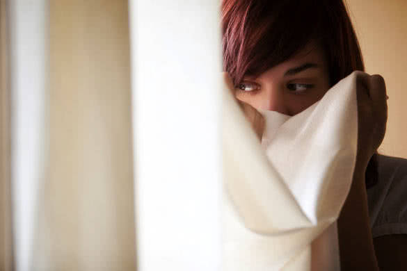 Timid girl hidden behind curtains