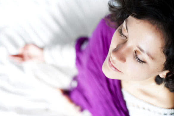 Young beautiful woman doing meditation on bed