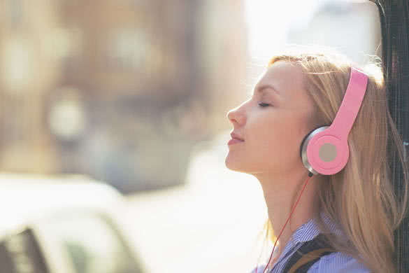 Young woman listening music in headphones in the city