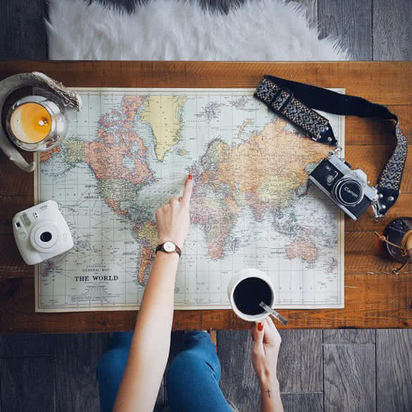 Young woman picking the place on map and drinking coffee