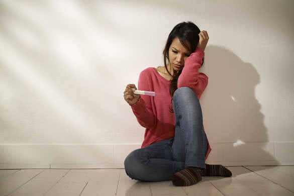 anxious Asian girl looking at pregnancy test kit