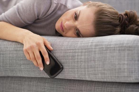 sad-woman-laying-and-holding-phone