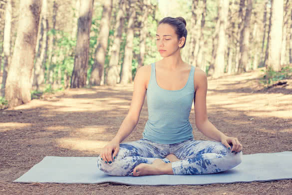Beautiful happy young woman meditating doing yoga outdoors in summer autumn park