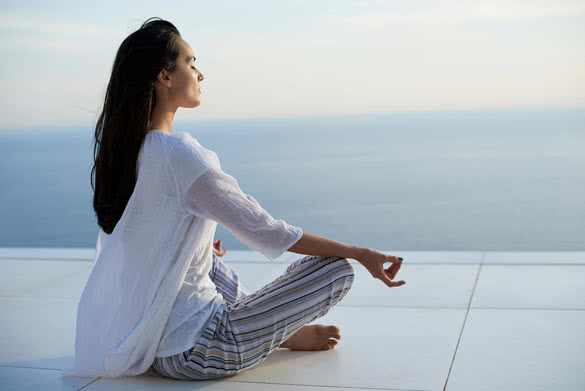 young woman practice yoga meditaion on sunset with ocean view in background