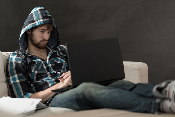 man sitting on a couch looking at a laptop