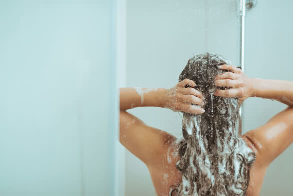 Young woman washing head with shampoo