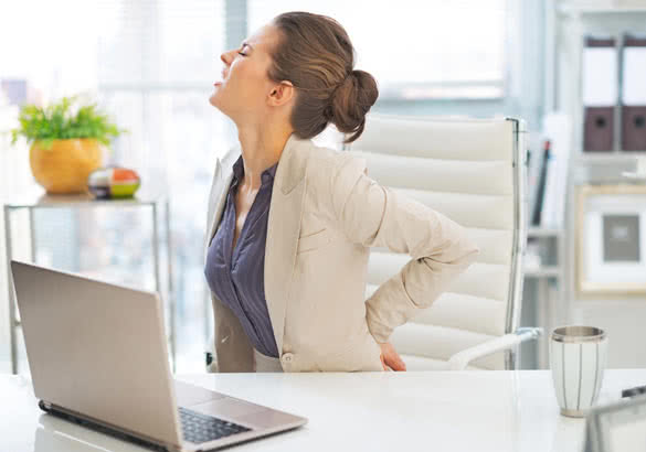 business woman with back pain in office