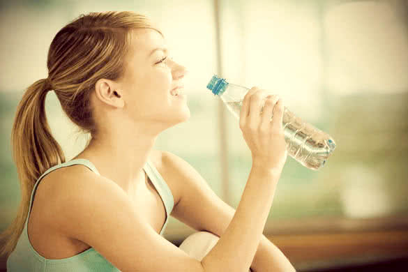fit woman with ponytail drinking water