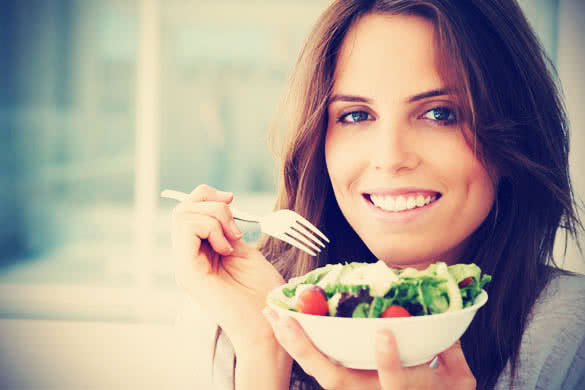 smiling woman eating vegetable salad