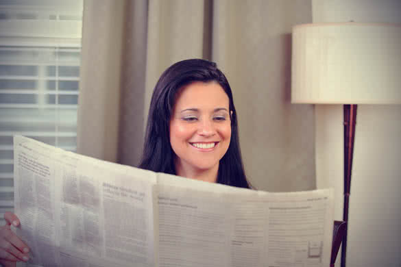 woman reading newspaper at home