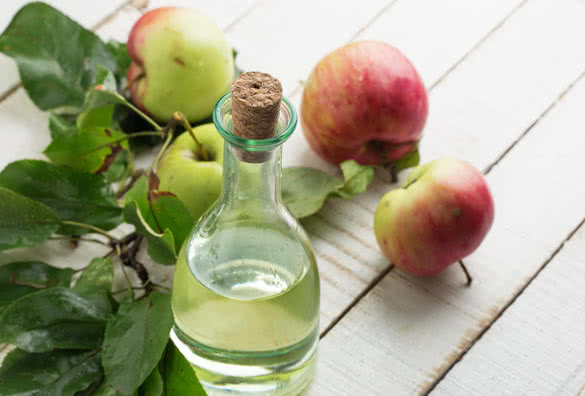Apple vinegar and apples on white wooden table