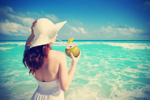 Woman looking at the ocean and drinking Coconut Water