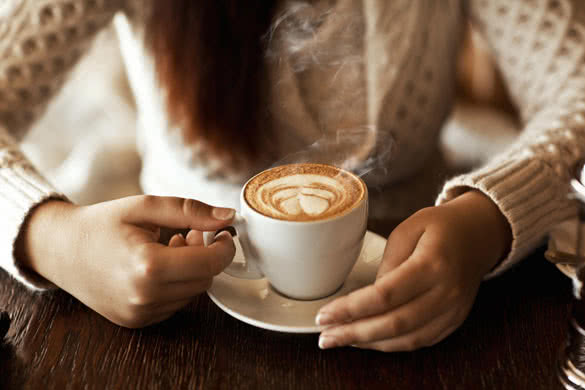 woman hands with latte on a wood table