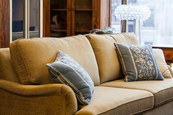 A light brown sofa with blue and cream pillows