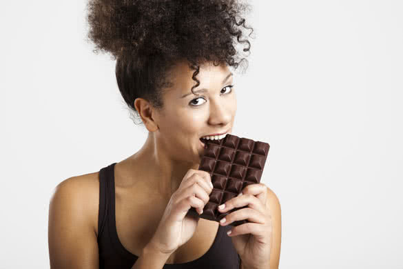 Beautiful african woman holding and eating a huge dark chocolate bar