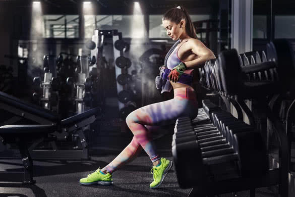 Fitness girl with towel and shaker relaxing in the gym