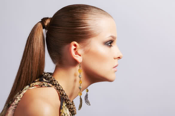 beautiful young long-haired brunette woman in ear-rings on gray