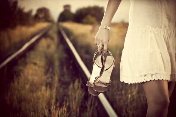 young woman hand with shoes on the railway