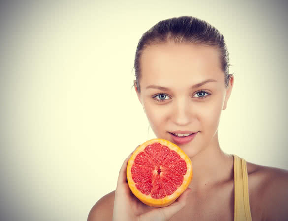 Happy girl with grapefruit in her hand