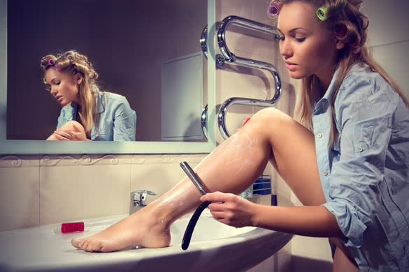Woman shaving her legs in the bathroom