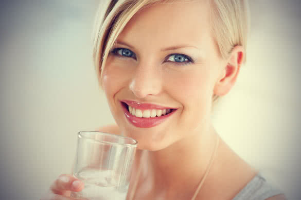 blonde woman with short haircut drinking a glass of water