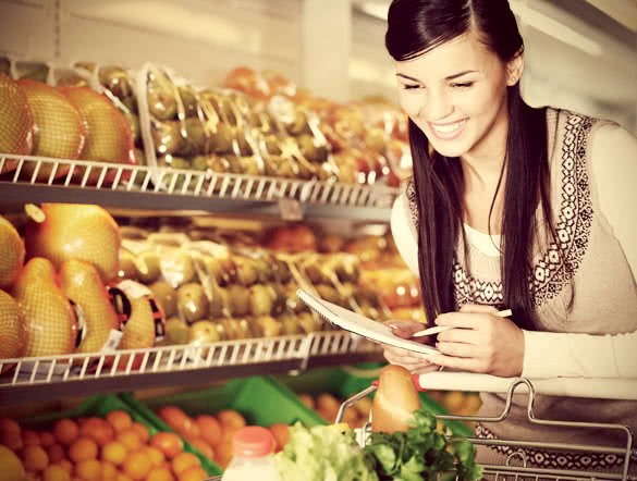 pretty woman choosing products in supermarket with list of things to buy