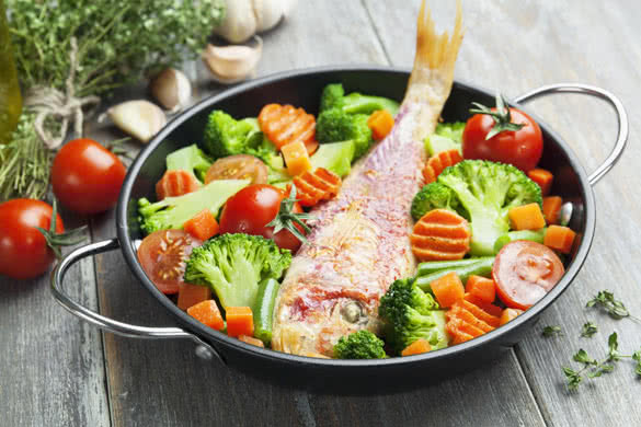 Fried fish with vegetables in the pan