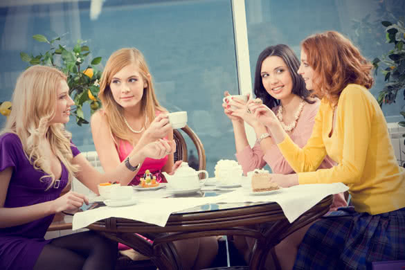 four young women sitting at the table in the cafe