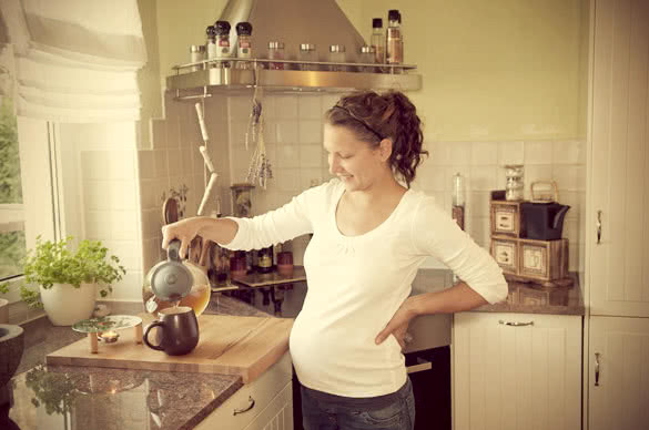 pregnant woman preparing tea at home