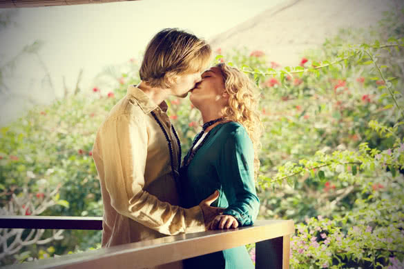 Young couple kissing on a tropical home balcony