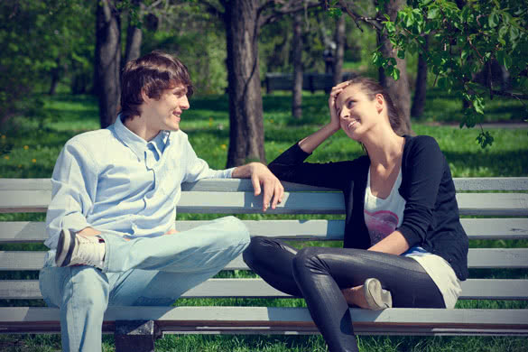 man and woman talking while sitting on bench