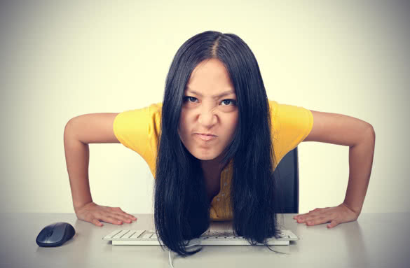 young girl making a mean face while at desk with computer