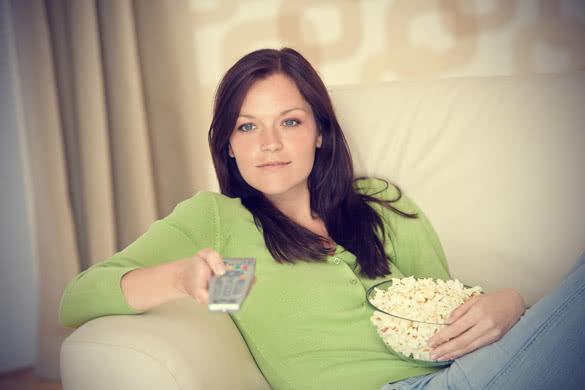 woman eating popcorn and watching television