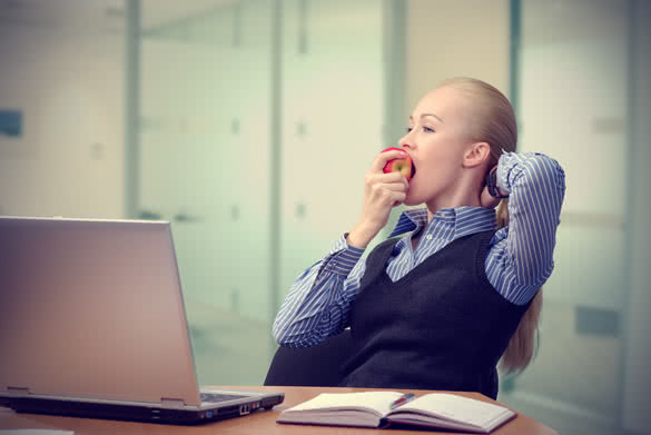 young beautiful business lady at table resting and eating an apple