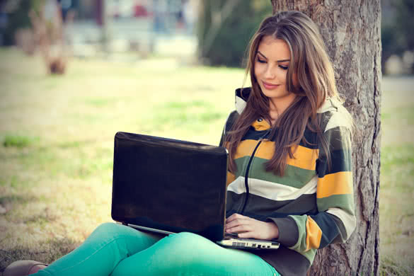 young woman with laptop relaxing in the park