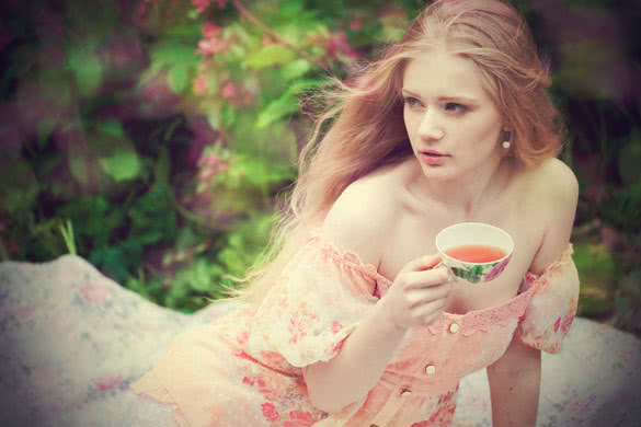 Beautiful woman with flowering tree drinking tea