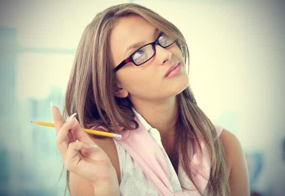 portrait of pensive girl in eyeglasses holding pencil