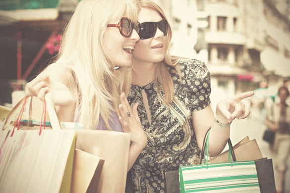two girl with shopping bags looking at shopping window