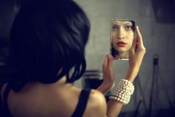 woman looking herself in mirror