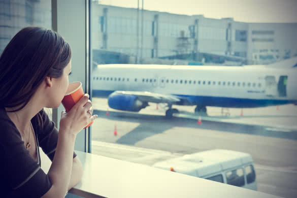 young woman is drinking coffee in airport