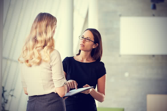 Two Businesswomen Having Informal Meeting In Modern Office