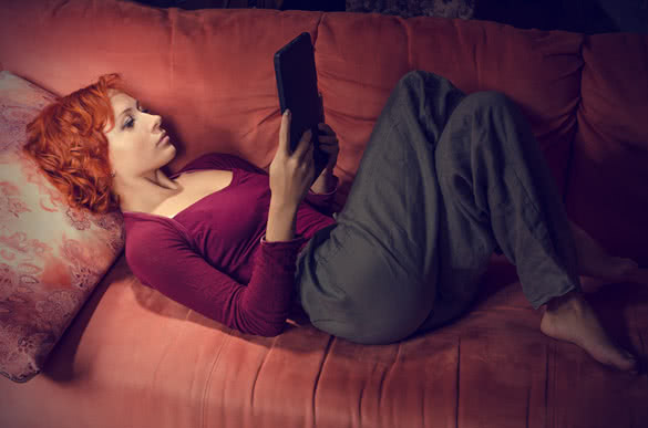 ginger woman lying on her couch with tablet