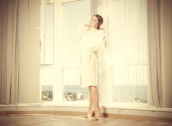 young happy woman enjoying sea view in hotel  room next to big window