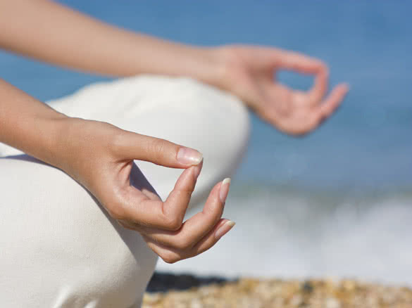 female hands during meditation on beach