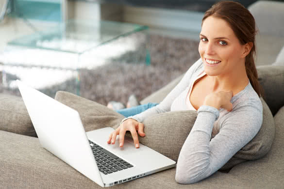 smiling young woman with laptop in her living room