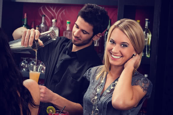 young happy girl at cocktail bar while bartender mixing drink
